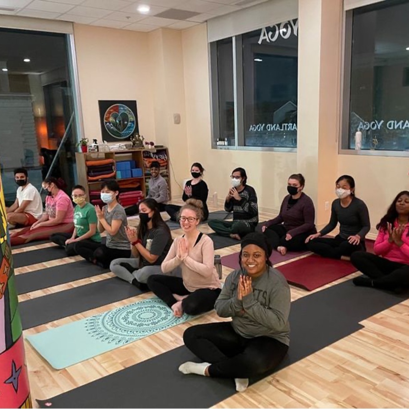 People smiling at the camera while sitting on yoga mats during a BGP event