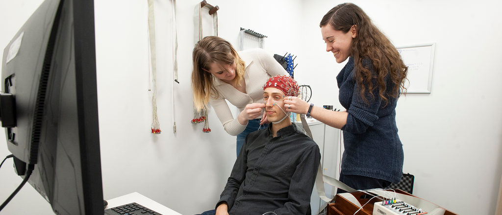 Person with a brain hat getting tested by clinical faculty and student